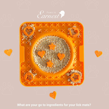 An orange lick mat from Paws in Earnest, filled with a textured mixture called Lickeeze and decorated with heart and star-shaped carrot pieces. 
